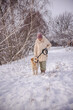 © StockMediaSeller - Elderly woman walking her Golden Retriever on a snowy countryside path. The woman gently looks at her dog while holding the leash, surrounded by snow-covered trees and soft winter sunlight.