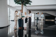© qunica.com - A team of professionals gathers in a bright, contemporary lobby. Some speak on phones, others review files and coordinate on tablets, reflecting collaboration and networking in a corporate setting.