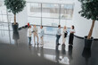 © qunica.com - Bright, glass-walled lobby where colleagues chat in smart casual outfits. Small groups share documents and ideas, showcasing collaboration, networking, and professional teamwork in a workplace.