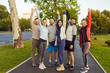 © Studio Romantic - Happy sporty young people in sportswear standing with hands up after successful sport exercises in summer park. Men and women having workout outdoors. Training and fitness in nature concept.