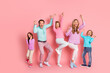 © deagreez - Family celebration in a pink studio with parents and kids jumping and smiling together in bright pastel outfits