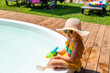 © yanadjan - A child plays in the pool with a water gun. Selective focus.