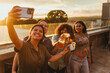 © STOCKEROcr - Happy friends making a toast and taking a selfie at sunset