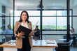 © PINA - asian businesswoman in formal suit standing at coworking space in green office, group of multiracial team colleague diverse employee coworker meeting at environment sustainable workplace