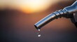 © Ameer - a close up of a fuel nozzle dripping gasoline at a gas station with a blurred background effect at sunset