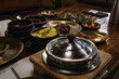 © cjfgks - Authentic Korean Full Course Meal (Hansik Hansang) served on traditional Yugi Brassware with Banchan, Gyeran-jjim, and Main Dishes in a Rustic Dining Setting.