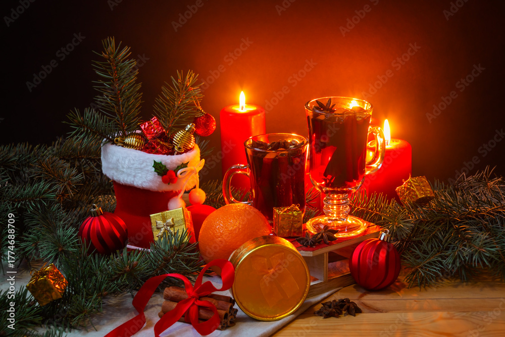 Glasses of mulled wine, burning candles, christmas stocking, christmas balls, pine branches, gifts and balls on wooden table. Christmas concept.