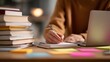 © Warakorn - close up of hands writing notes with books and laptop studying focus learning