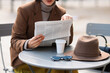 © New Africa - Woman in suit reading newspaper at table in outdoor cafe, closeup