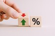 © The Little Hut - Interest Rate Fluctuation Concept: Hand Adjusting Wooden Blocks with Arrows Representing Rising and Falling Percentage