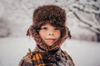 © RooM The Agency - Portrait of a smiling boy wearing a hunters cap standing in a snowy forest landscape in winter, USA