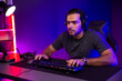 © InfiniteFlow - Smart gaming streamer concentrating gaming players trying to pass the level at mission completed, using headset and mic for communicate others on streaming live at neon lighting studio room. Surmise.