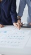 © rogerphoto - Professional team reviewing financial documents, pointing at charts on desk, collaborating to analyze data and strategize business growth. Business people concept