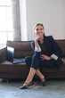 © Yevhen - Portrait of businesswoman leader in dark blue jacket at work with notebook. Female is sitting on the sofa