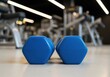 © Meow Creations - Pair of vibrant blue hexagonal dumbbells ready for a workout session in a modern gym.