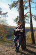© anna.stasiia - Portrait of smiling caucasian girl plays ukulele in autumnal park. Young woman plays guitar musical instrument outside in nature fall time. Audio music healing in natural surrounding.