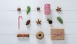 © VISIONER ADVANCE - Winter holiday flat lay concept with Christmas decorations, gift wrapping supplies, and natural elements like spices and pine cones on a white wood background
