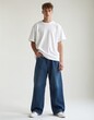 © Pete - Handsome young man poses in studio. He wears white t-shirt baggy jeans. Male model stands confidently. Guy looks at camera. Modern style fashion concept. Casual outfit