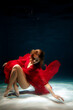 © Cavan Images - Woman in red dress gracefully poses underwater in serene blue setting