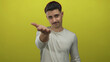 © Krakenimages.com - Young hispanic man presenting hand against vivid yellow background, conveying openness and invitation with a friendly expression.
