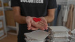 © Krakenimages.com - Hispanic man holding red heart symbol while smiling at camera in volunteer room surrounded by stacks of food trays exemplifying kindness and community support