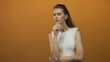 © Krakenimages.com - Woman with hand on chin thinking in studio with orange backdrop, slight frown and folded arm; doubt reflection.