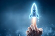 © Andrey_Lobachev - Hand touches a digital rocket, symbolizing the launch of innovation and future technology.