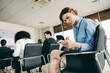© deagreez - Businesswoman checking phone during conference in modern office space among diverse coworkers focusing on presentation