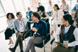 © deagreez - Diverse business team attentively listening to a conference speaker in a modern professional workspace
