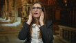 © Krakenimages.com - Woman in glasses covering ears with hands inside ornate church nave with stained glass and closed eyes and open mouth; discomfort.
