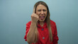© Krakenimages.com - Woman shouting with clenched fist and furrowed brow against light blue backdrop in studio; anger defiance empowerment resilience.