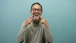 © Krakenimages.com - Mature man pointing to his smile while standing against a plain blue background, expressing happiness with his gesture and facial expression.