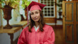 © Krakenimages.com - Young woman in graduation gown stands in a beautifully decorated hotel room, showcasing proud academic achievement and transition into a new life chapter.