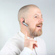 © photosaint - Man in white shirt using a wireless headset while smiling and engaging in conversation
