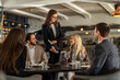 © Creative Light - Server presenting champagne to a group of friends at a restaurant table