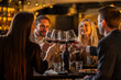 © Creative Light - Friends toasting with red wine at a restaurant, celebrating a special occasion.