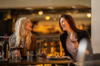 © Creative Light - Two women laughing while enjoying wine and food at a restaurant