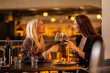 © Creative Light - Two women toasting with red wine glasses at a restaurant, celebrating a special occasion