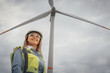 © YURIMA - A confident female engineer stands proudly before a towering wind turbine, symbolizing the bright future of renewable energy and our commitment to environmental sustainability for generations