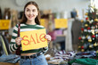 © JackF - Girl with poster in hands announce mega Black Friday discounts in womens clothing store. Hostes presented hold advertisement with inscription price reduction, announced mega SALE
