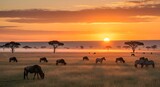 African savanna landscape with wildebeest and zebras grazing at sunrise under acacia trees