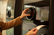 © Westend61 - Hand inserting plastic bottle into reverse vending machine for recycling
