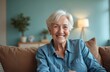 © Vadym - Senior lady with white hair smiling at camera. Elderly woman sitting on brown couch in living room. Mature female with toothy smile looking happy, cheerful. Older person on video call, enjoying
