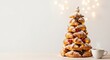 © kilimni - Christmas tree made of fresh baked croissants and cup of coffee nearby. Light festive background with copy space. Holiday banner for bakery and pastry shop. Christmas morning breakfast