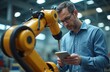 © Vadym - Caucasian man in blue shirt uses digital tablet. Engineer works with industrial robot arm in modern factory. Controls automation tech, monitors machine on production line for smart manufacturing