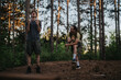 © qunica.com - Two backpackers stand in a pine forest during a hike, displaying energy and camaraderie.
