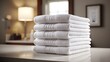 © Oleksandr - A stack of white, neatly folded towels on a vanity in a bathroom setting. A warm lamp and framed art contribute to a clean, comfortable ambiance. Perfect for relaxation.