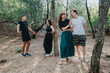 © qunica.com - Four friends spend time in a wooded area, chatting and smiling as they lean against trees. Casual outfits and a relaxed mood convey outdoor leisure, friendship, and carefree moments in nature.