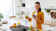 © Home-stock - Happy young pregnant woman using her smartphone and having snack, eating apple standing in well-lit kitchen interior