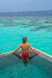 © Kyrenian - Tranquil closeup calm sea water waves with palm trees. Man tourist posing, Tropical island beach landscape exotic shore coast. Summer vacation, holiday amazing nature. Relax paradise, Maldives.